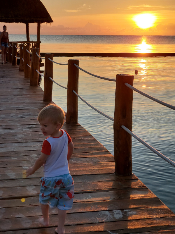 Young boy taking first steps towards a happy sunrise.