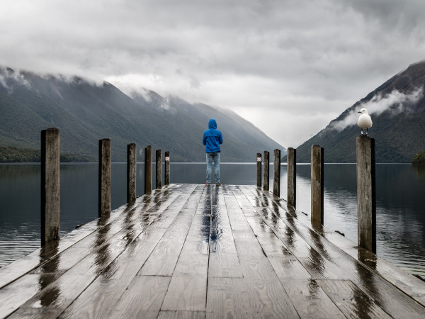 Man suffering from depression looking out from a serene dock.