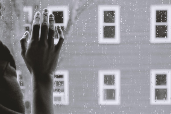 Hand of a person needing couples therapy on a window during a depressing rainstorm.